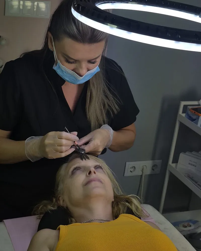 Liliya Lysa midiendo la ceja de una clienta para diseñarla a medida